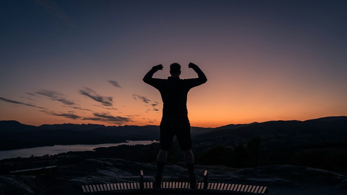 a man standing on top of a bench at sunset